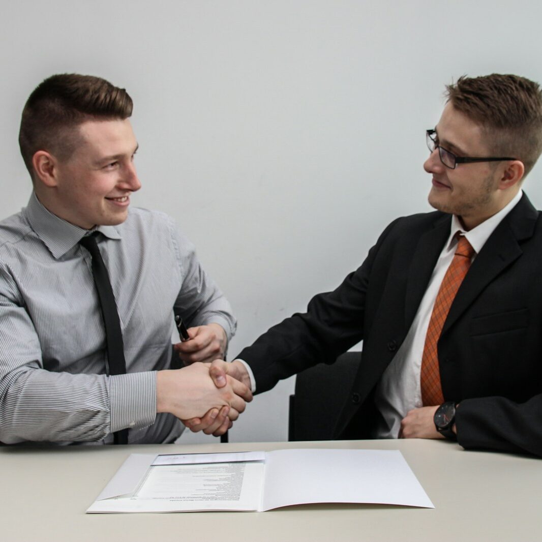 two men facing each other while shake hands and smiling