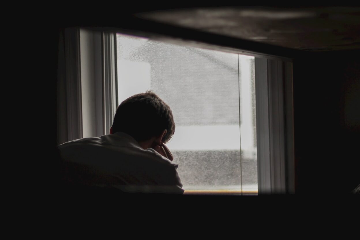 man looking outside by window