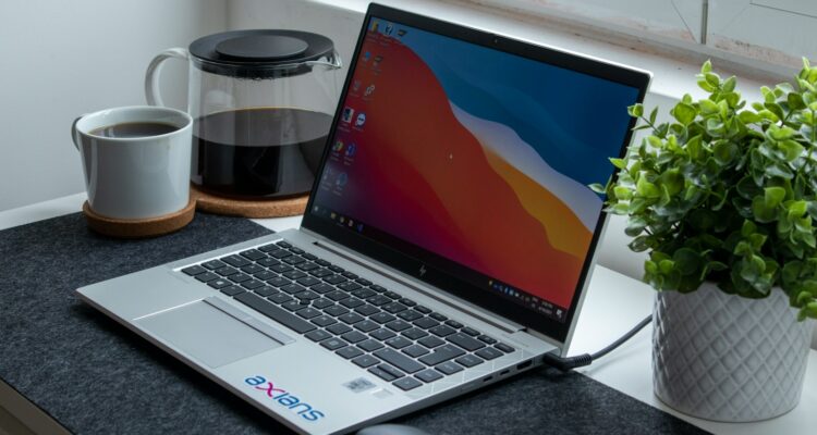 macbook pro beside white ceramic mug on black table